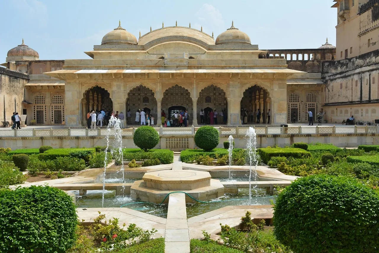 A formal garden with fountains in front of a white marble palace