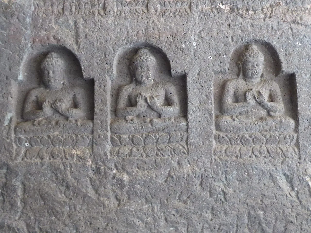 Rows of small carved Buddhas in a rock wall