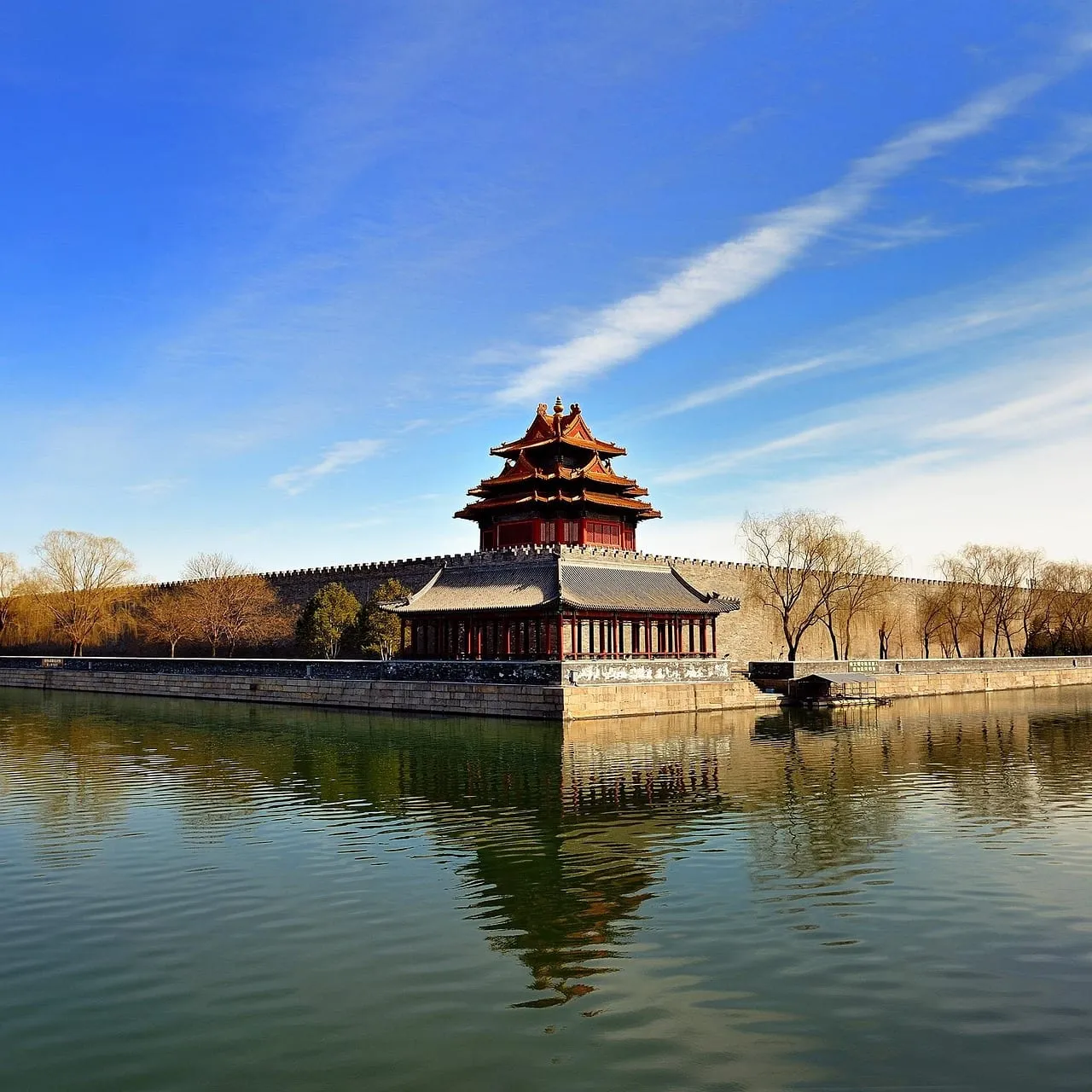 A corner tower of the palace wall reflected in the moat