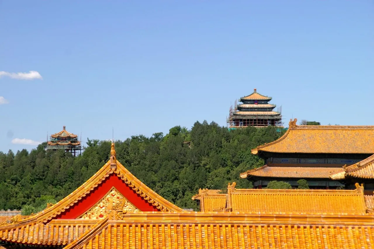 Yellow-tiled palace roofs, with a hilltop pavilion in the green park behind