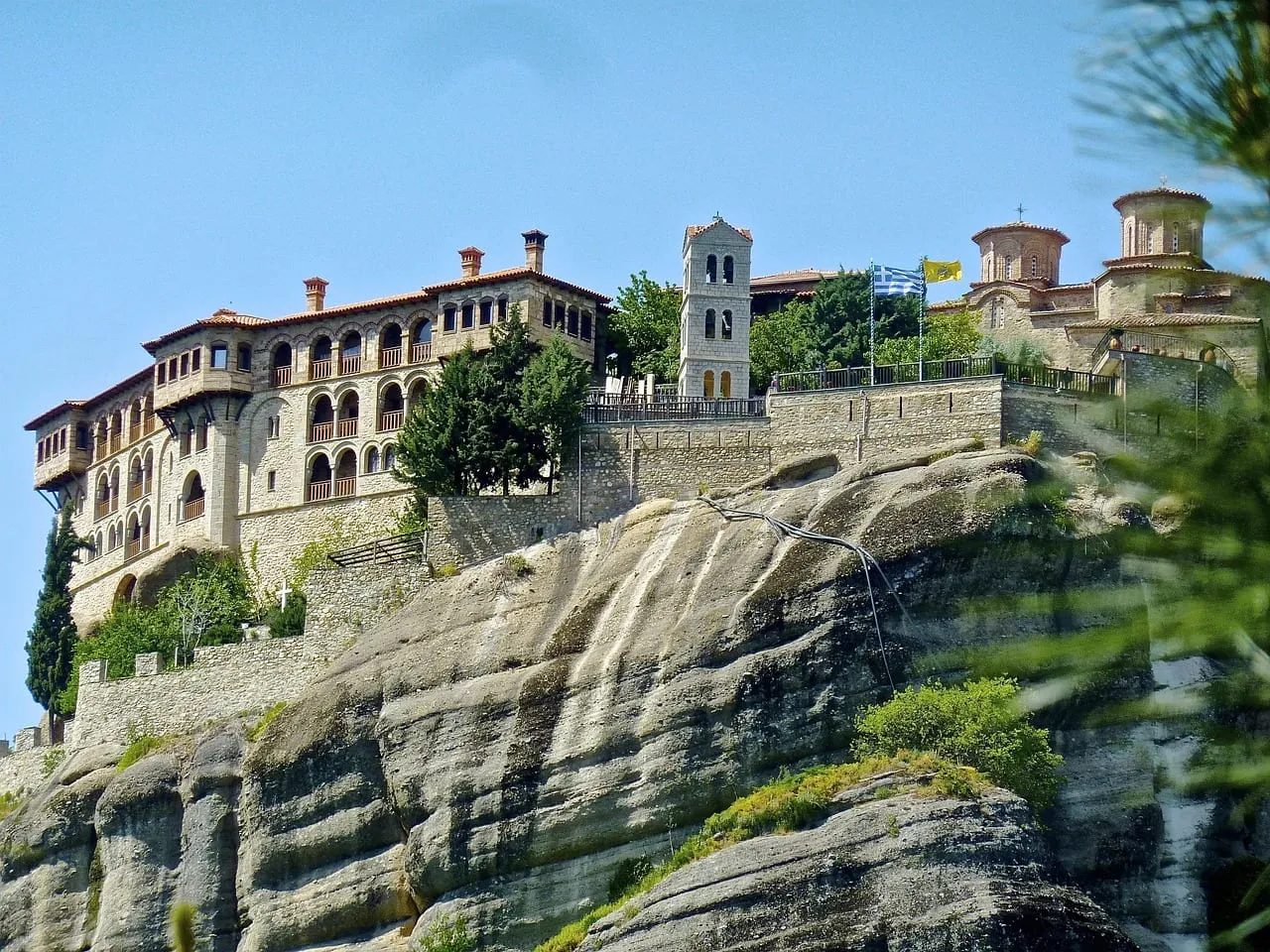A large monastery with a bell tower on a rock ledge
