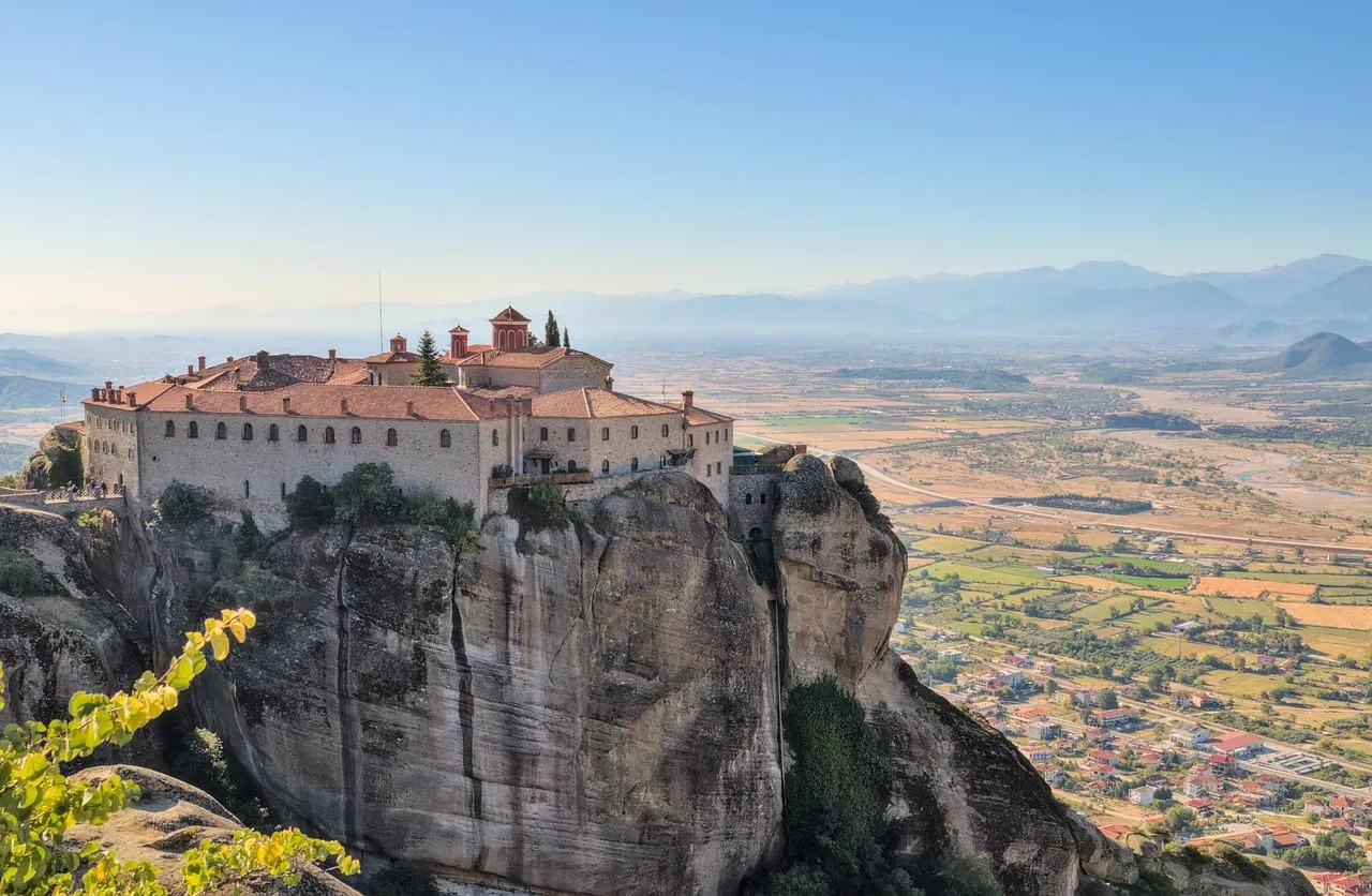 A monastery on a cliff top, with the plain stretching out below