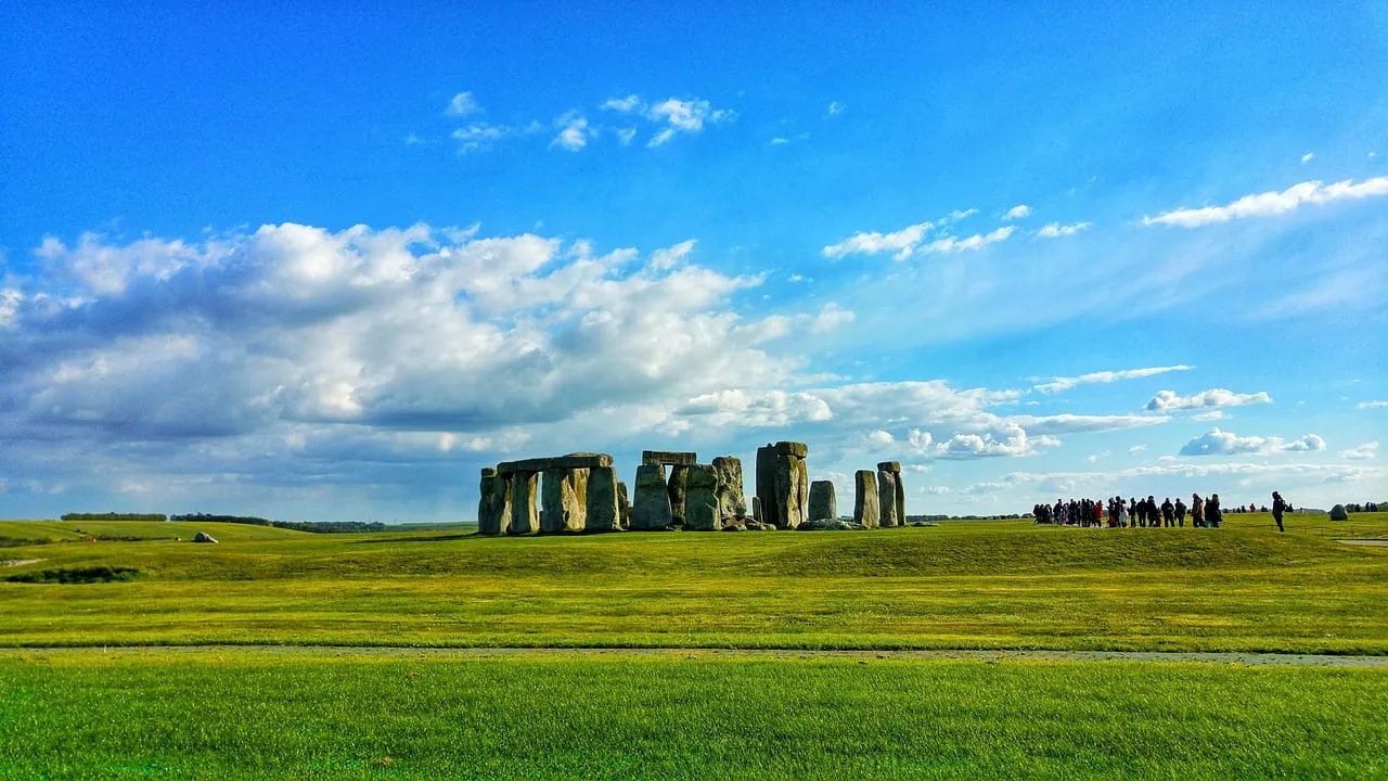 The stone circle seen from a distance across open grass, with visitors on the path