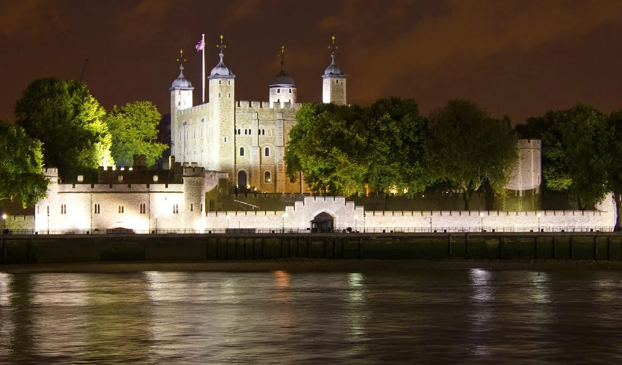 The Tower of London lit up at night across the river