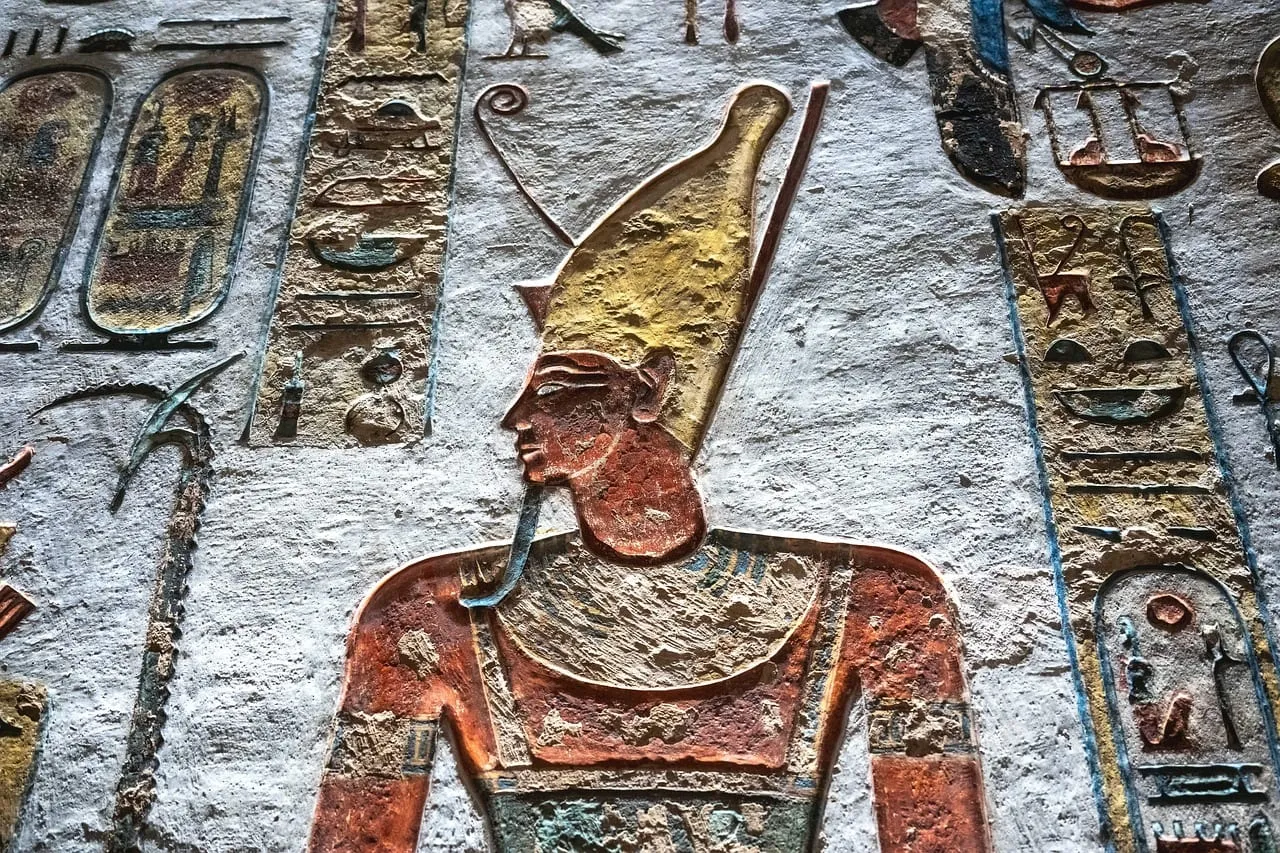 A painted relief of a king in a tall crown on a tomb wall