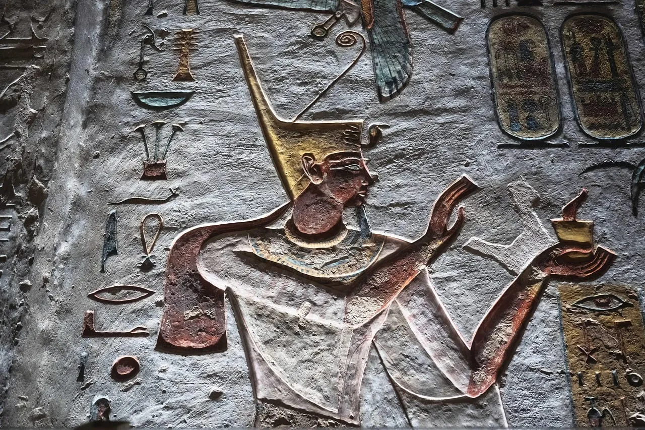 A carved and painted king making an offering, with hieroglyphs around him